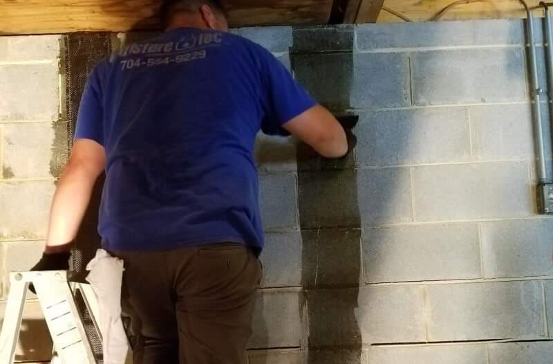 A Moisture Loc specialist examines a wall receiving basement wall repair.