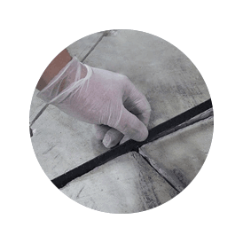 A technician measures a crack in preparation for concrete slab repair servicing.