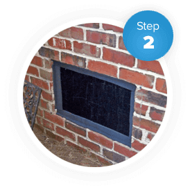 A brick building's exterior crawl space vent is sealed as part of the seal vent encapsulation process.