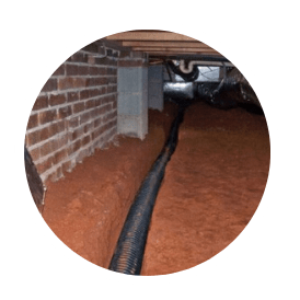 A crawl space drainage system is dug into the ground beneath a building's foundation.