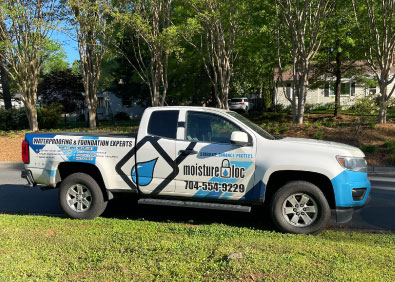 A Moisture Loc basement waterproofing foundation repair truck sits on the grass.