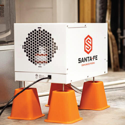 A white Santa Fe basement dehumidifier system on orange leg stands.