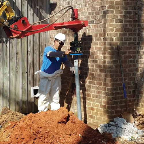 A Mosisture Loc worker in safety gear conducts foundation settlement repair on a home.