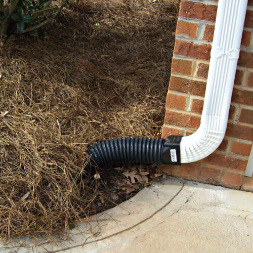 A black plastic yard drainage system is installed by yard drainage contractors.