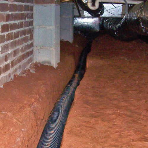 A crawl space draining system sits in a trench during the installation process.