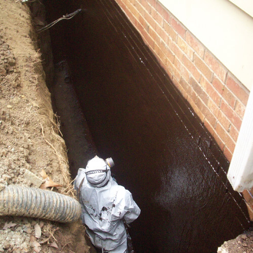 A Moisture Loc technician works underneath a building to repair damage with crawl space waterproofing services.